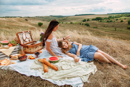 Beautiful young girls girlfriends on a picnic on a summer day. The concept of leisure, privacy, communication, vacation, tourismの写真素材