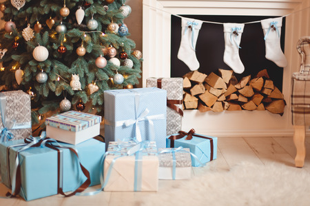 Photo of interior of room with a wooden wall, wreath and garlands, Christmas tree, fireplace with firewood. Christmas atmosphere. Home comfortの写真素材