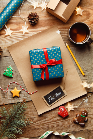 Beautiful Christmas background with a new year dÃ©cor, a sheet of old paper, garland and gifts, gingerbread and a Cup of tea on a wooden background. Merry Christmas postcard.の写真素材