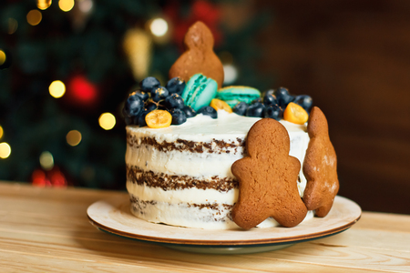 Beautiful decorated cake with gingerbread men for Christmas table on New Year bokeh background. Preparing for a family celebrationの写真素材