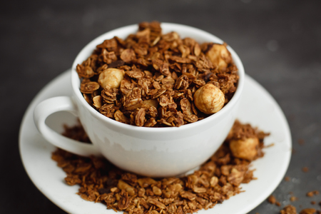 Granola in a white Cup on a black background. The concept of a healthy diet, weight loss, dietの写真素材
