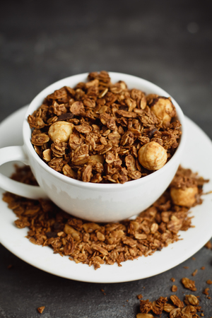 Granola in a white Cup on a black background. The concept of a healthy diet, weight loss, dietの写真素材
