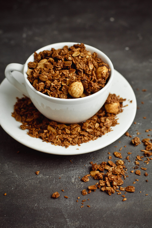 Granola in a white Cup on a black background. The concept of a healthy diet, weight loss, dietの写真素材