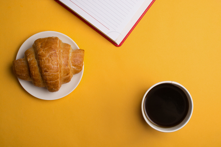 Cup of coffee and enjoy notebook on yellow Background.の写真素材