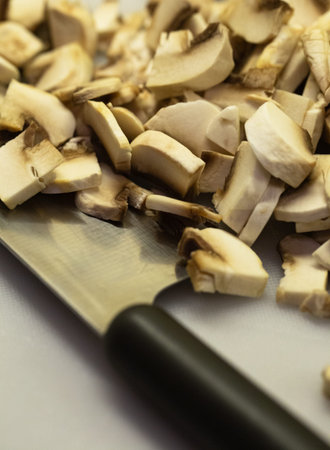 Sliced champignons mushrooms on a kitchen board with a knife