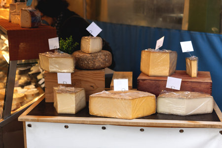 Artisan Cheese Display at Market Stall with Various Cheese Wheels