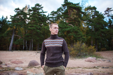 A man stands on a rocky beach on the background of the forestの写真素材