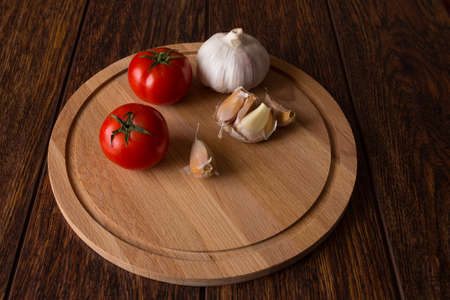 Tomatoes and garlic on a wooden boardの写真素材