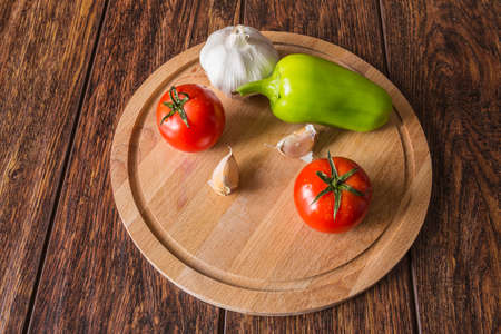 Vegetables on a wooden Board (tomatoes, peppers, garlic)の写真素材
