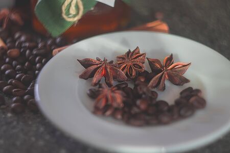 Glass jar with honey covered with green cloth with thread with white paper heart for Valentine's Day. White plate. Star anise star anise, cinnamon sticks, coffee grains.の写真素材