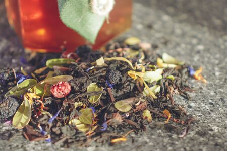 Natural tea brewing of dried berries and leaves of medicinal plants. Glass jar of honey with a lid of natural fabric tied with a thread with a paper heart. Natural products for Valentine's Day.の写真素材