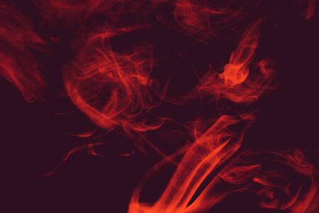 Curls and clouds of colored smoke float against a colored dark background.の写真素材
