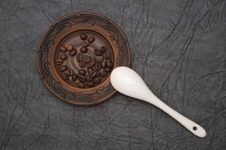 Homemade saucer made of glazed clay. A pinch of brown roasted aromatic coffee beans.の写真素材