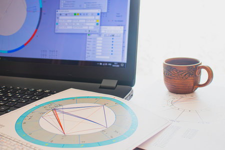 Workplace of a modern astrologer. Astrological charts, diagrams, tables scattered around the table....