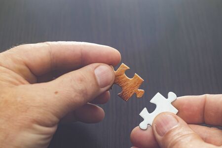 Hard to solve the problem. Collapsible puzzle pieces. Hard to solve the problem. Collapsible puzzle pieces. Puzzle pieces scattered across the table. Hands of a man.の写真素材