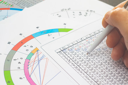 The magic of the workplace of a modern astrologer. Astrological charts scattered across the table,...