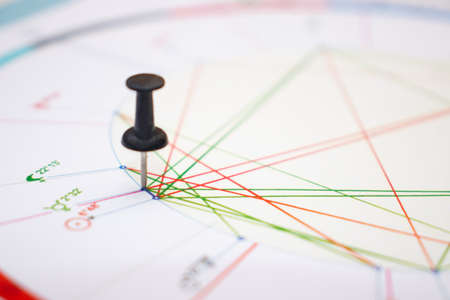 Setting a confusing astrological task. A black pin pinned to an astrological chart at the location of the aspect in question. Symbols of zodiac signs, planets, aspects.の写真素材