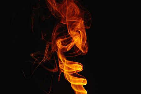 Orange smoke on a black background. Colored smoke. Smoke illuminated by orange light. Bizarre spellbinding flames.の写真素材