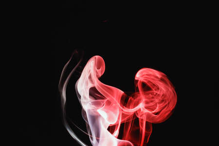 Red smoke on a black background. Colored smoke. Incense stick smoke, illuminated by red light.の写真素材