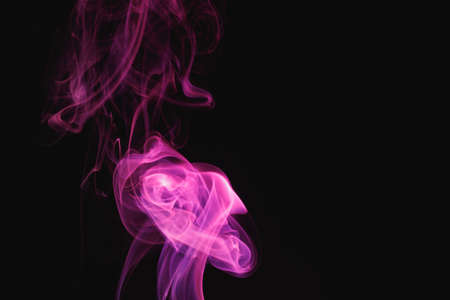 Purple smoke on a black background. Colored smoke. Incense stick smoke illuminated by purple light.の写真素材