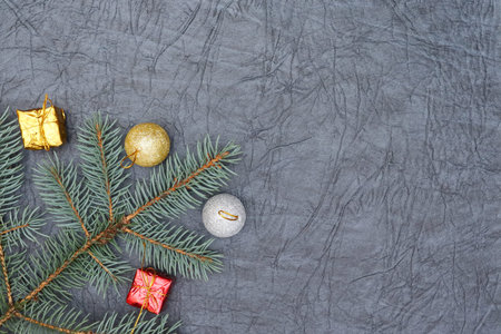 Merry christmas and a happy new year! A sprig of the green symbol of the winter holidays - spruce with decorations on a background of gray artificial leather backing.の写真素材