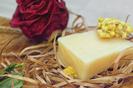 The use of natural products. A handmade piece of fragrant soap on paper chips surrounded by flowers...