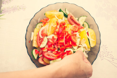 Brown glass plate with salad. Salad of red, yellow tomatoes, green cucumbers, onions.