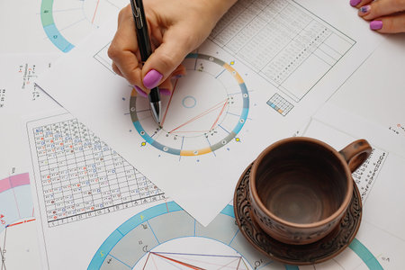 Workplace of a modern astrologer. Printouts of astrological charts, charts, tables, diagrams lying...