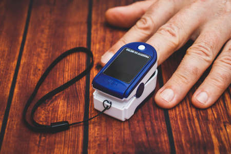Small digital device for measuring pulse and blood oxygen level. Oximeter on a man's fingerの写真素材