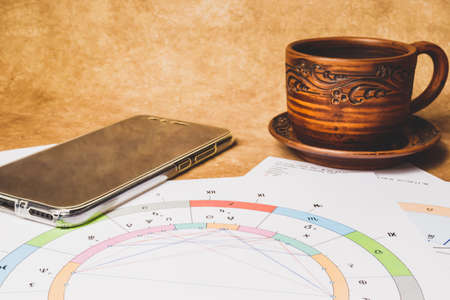 The workplace of an astrologer, magician and sorcerer of our time. Hobby during the pandemic. Astrological charts and tables built with the help of modern gadgets, laid out on the table.の写真素材