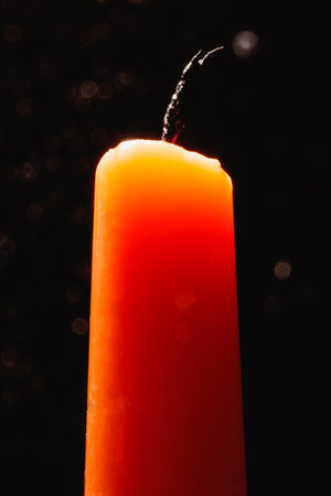 An extinguished orange candle against a dark background in the backlight.の写真素材