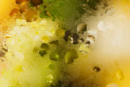 Water vapor droplets on the glass lid of a frying pan with stewed vegetables. Colored background...