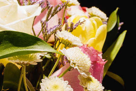 Spring bouquet of bright multi-colored flowers close-up. Bouquet of roses, tulips in green leaves.の写真素材