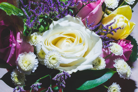 Spring bouquet of bright multi-colored flowers close-up. Bouquet of roses, tulips in green leaves.の写真素材