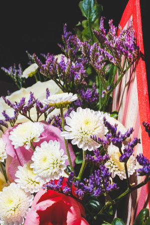 Spring bouquet of bright multi-colored flowers close-up. Bouquet of roses, tulips in green leaves.