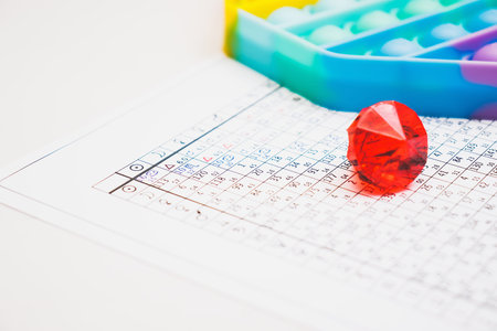 Modern astrologer's desktop.   a red glass pebble on the table. Astrological charts and tables with...