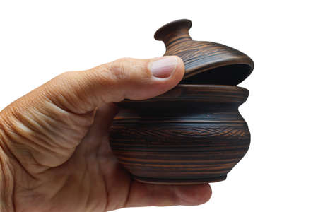 Brown ceramic sugar bowl in hand close-up. Isolated. A vessel with a lid for sugar in the hands of a man on a light background.の写真素材