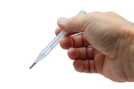 Mercury thermometer to measure body temperature in the hand. Isolated. The thermometer in the man's...