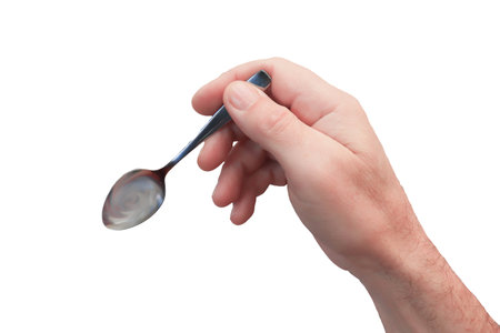 A metal teaspoon in the man's hand is close-up on a white background. isolate.の写真素材