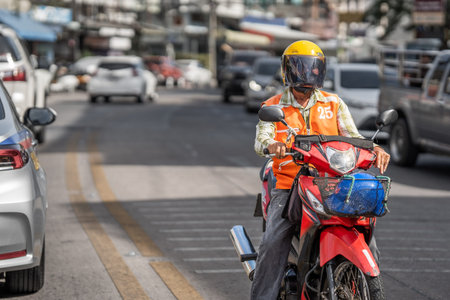 Thai courier on a motorcycle in city trafficの写真素材