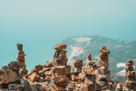 Pyramids of stones on a hill, the outlines of a tropical island in the distance. The concept of travel and excursionsの写真素材