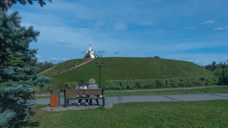 Elderly people on a bench in a summer city Park in front of the Churchの写真素材