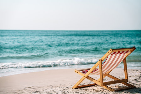 Chaise lounge on the sea sand on the coast of the azure sea and against the blue sky, the concept of relaxation on a tropical islandの写真素材