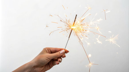 Hand holding a lit sparkler. Use for celebration blogs, holiday themes, party supplies, festive designs, New Years Eve, firework safety.の素材