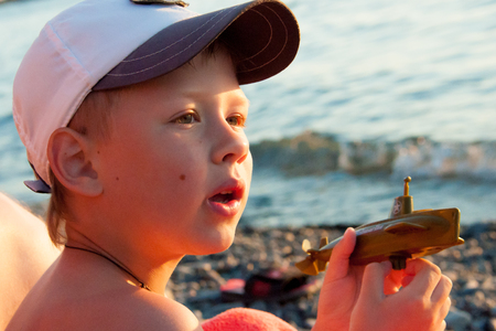 thoughtful boy near the sea with a toy submarineの写真素材