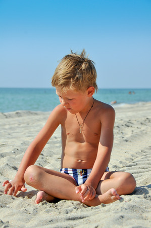 boy sitting on the sand near the sea summer sunny dayの写真素材
