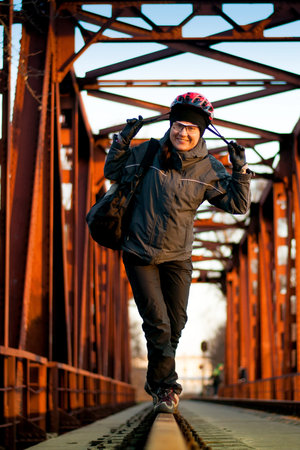 Woman standing on the rails in a helmet on a background of a metal bridge