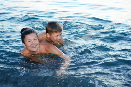 mother with son bathing in the sea having fun and laughingの写真素材