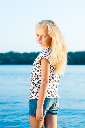 Girl standing on the sand near the water on a summer dayの写真素材