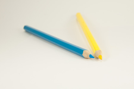 two pencils yellow and blue on a white background closeupの写真素材